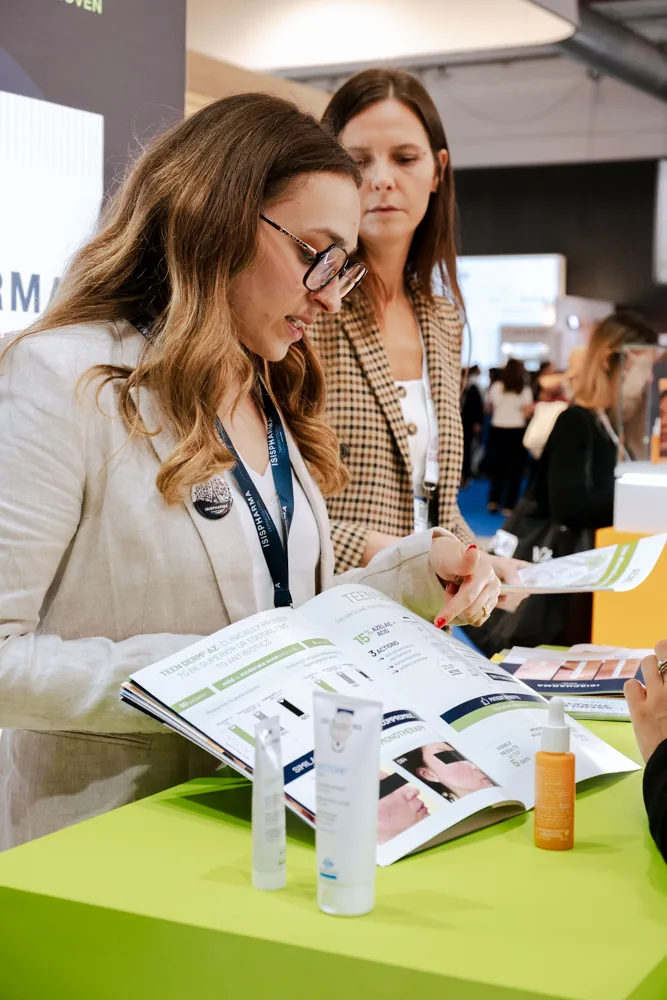 Deux visiteuses consultent une brochure sur le stand Isispharma